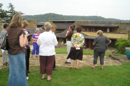 Photograph of Keiran with a tour group on Taliesin's Hill Crown. Keiran has white pants on.