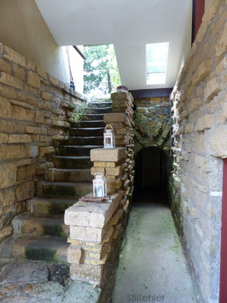 Photograph looking south at steps and root cellar behind stone arch on right. Taken by Stilfehler in 2018