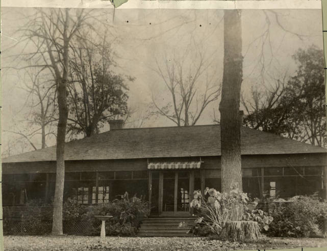 Photo is sepia of cabin with hipped roof surrounded by trees in late fall. Property: https://digitalcollections.hclib.org/digital/collection/MplsPhotos/id/12037/